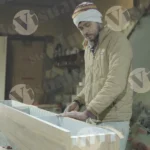 Carpenter tapping plywood shelf wide shot - log, colour and B&W