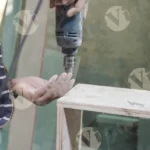 Carpenter installing nails on plywood with a nail machine - log, colours and B&W