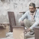 Carpenter continue making designs on wood wide shot - Log, colour and B&W