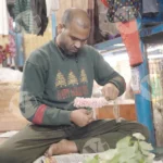 Man stringing flowers on thread - Log, colour and B&W