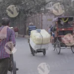 A man on a handcart carrying a large load of packages - Log, colour and B&W