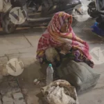 A beggar is sitting on the road and something eating - Log, colour and B&W