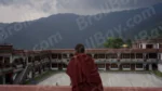 A Monk Standing in a Courtyard of  a Building with aLarge Mountain in the Background - Log, colour and B&W