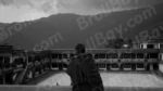 A Monk Standing in a Courtyard of  a Building with aLarge Mountain in the Background - Log, colour and B&W - Image 2