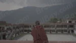A Monk Standing in a Courtyard of  a Building with aLarge Mountain in the Background - Log, colour and B&W - Image 3
